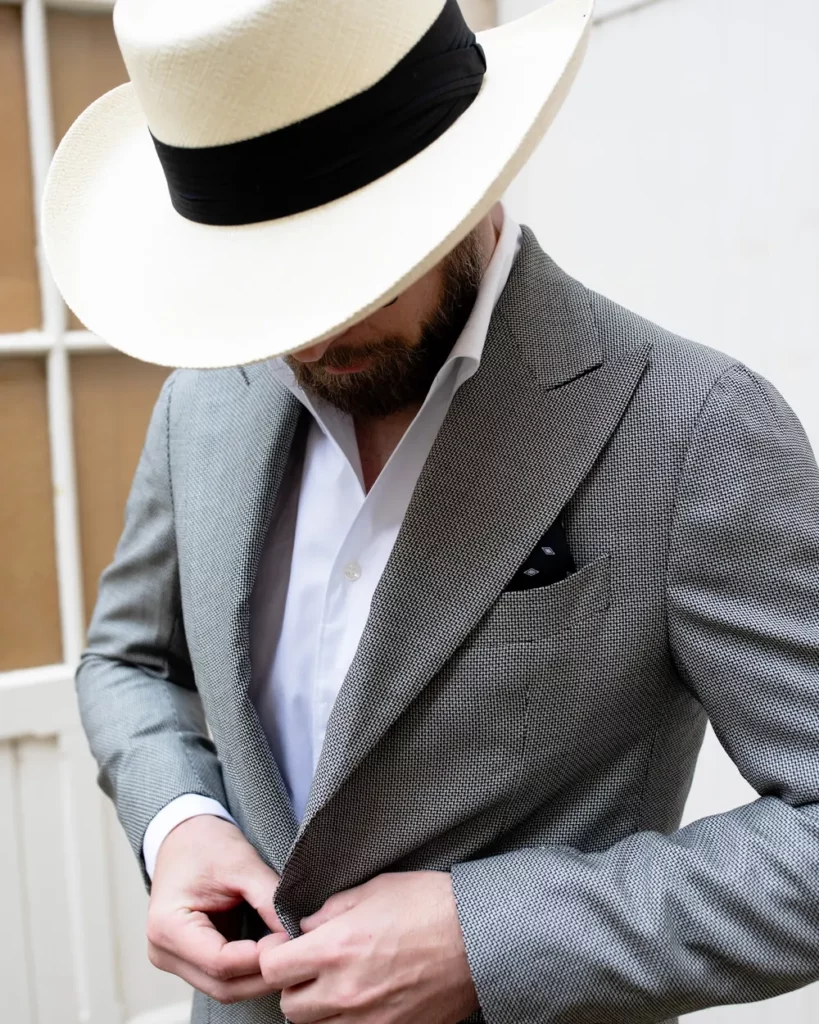 Costume sur mesure gris chiné porté avec un panama