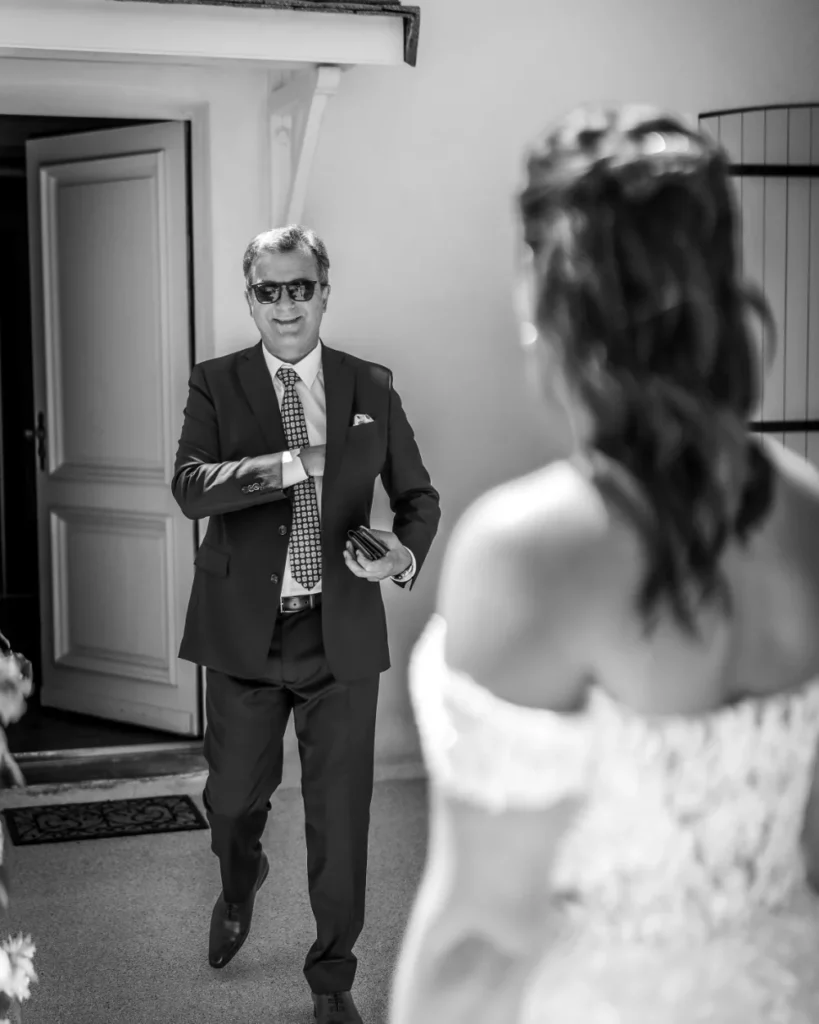 Le père de la mariée, en costume sur mesure Auguste, conduit sa fille à l’autel