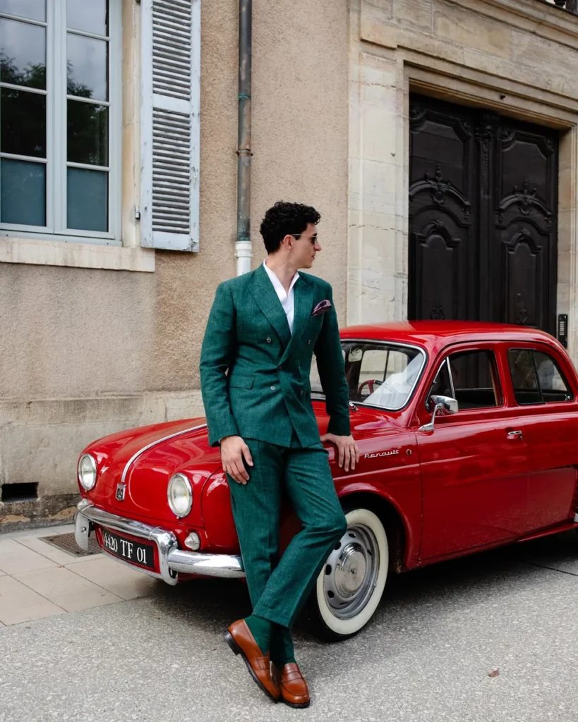 Costume vert sur mesure devant une voiture rouge