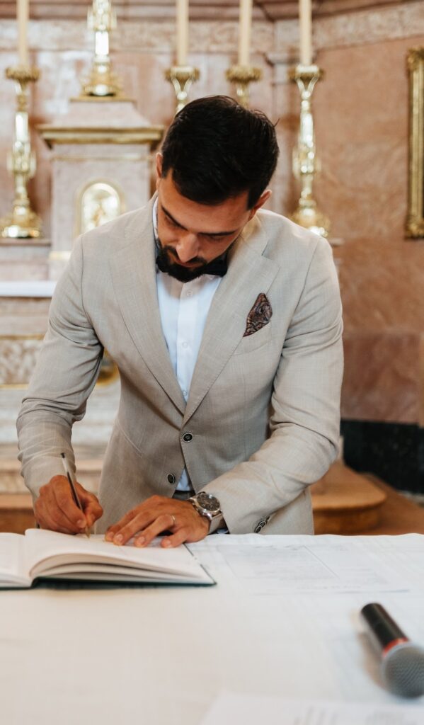 Alexandre, témoin, signe le registre en costume beige