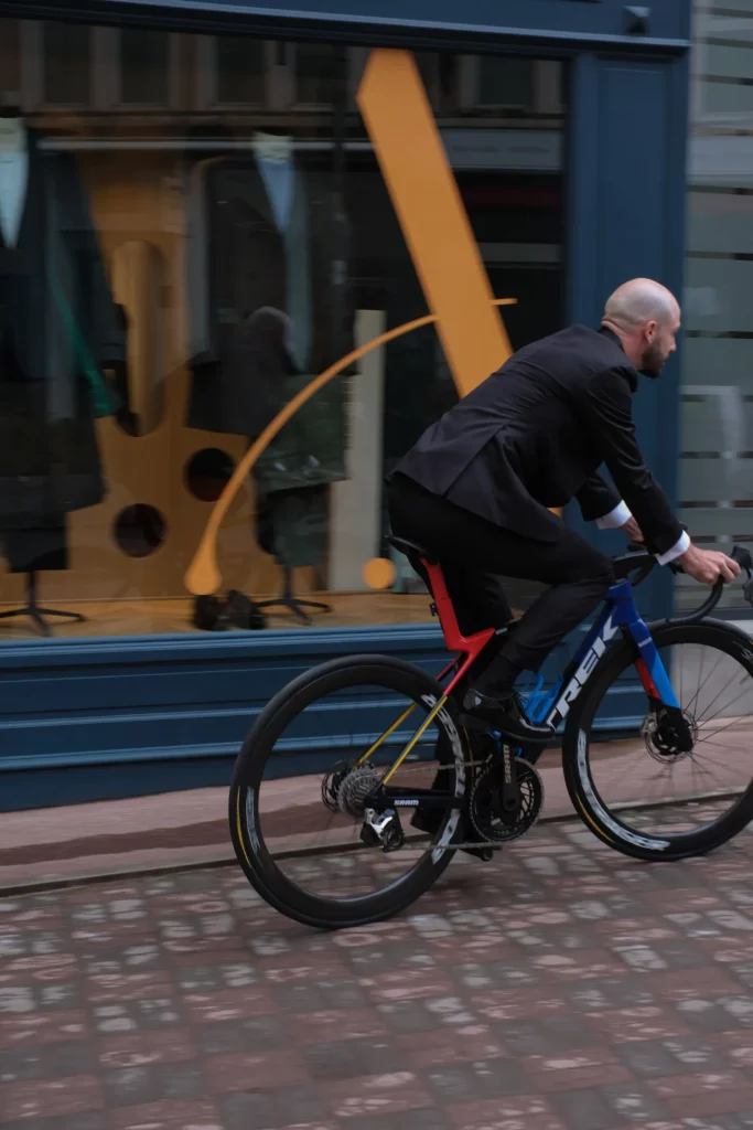 Julien Bernard à vélo en smoking devant la boutique Auguste