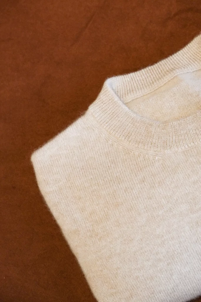 Le col d’un pull écru en maille fine